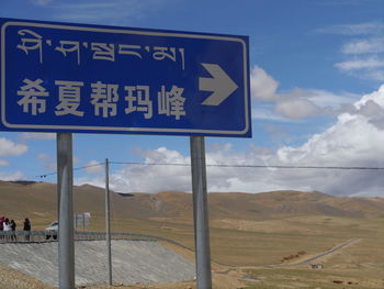 Sign board against cloudy sky