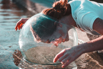 Close-up of woman wearing glass container at lake