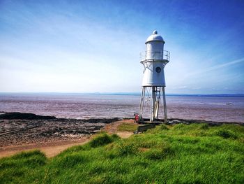 Lighthouse by sea against sky