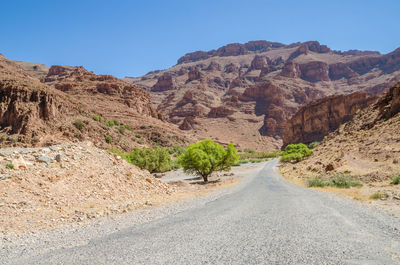 Road amidst rocky mountains against clear sky