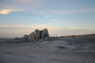 Rock formation on beach against sky during sunset