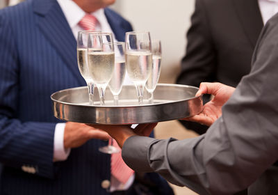 Midsection of waiter serving drinks at event