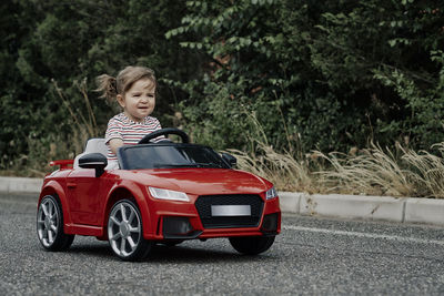 A girl riding a toy car