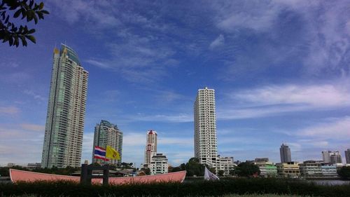 Low angle view of skyscrapers against cloudy sky