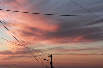 Low angle view of silhouette street light and cables against sky during sunset