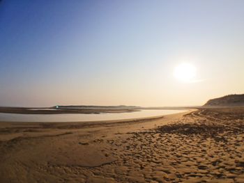 Scenic view of beach against clear sky during sunset