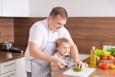 Father and son at home standing in the kitchen together, man smiling