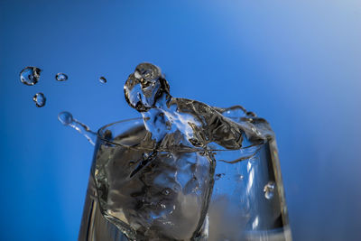 Close-up of splashing water against blue background