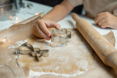 The child's hands make cookies from dough with a mold, the rolling pin lies near the dough 