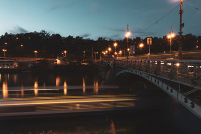 Illuminated bridge over street against sky at night