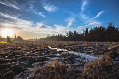 Scenic view of snowy field against sky during sunset