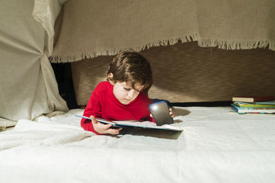 Cute boy lying on floor while reading book