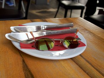 Close up of cutlery and sunglasses in plate on table