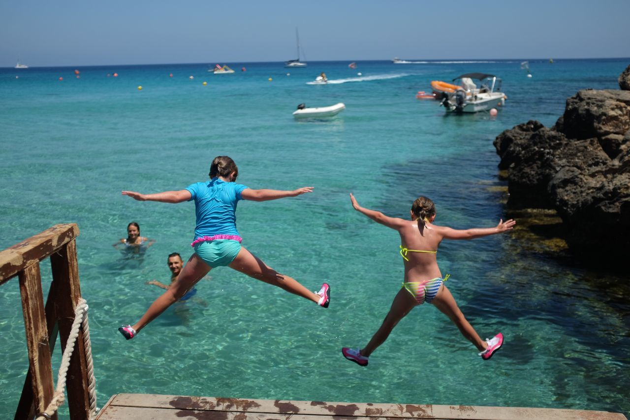 sea, jumping, mid-air, full length, water, day, two people, real people, arms outstretched, shirtless, outdoors, togetherness, men, vacations, motion, lifestyles, swimming, scenics, horizon over water, nature, young adult, adult, people