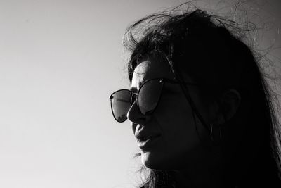 Close-up of young woman wearing sunglasses against clear sky