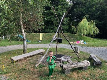 Boy playing on field against trees