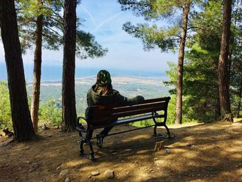 Full length of man sitting on bench on mountain