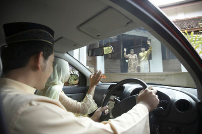 Parents waving at children in car