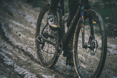 Low section of person riding bicycle on wet dirt road