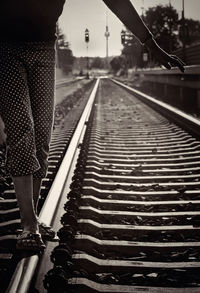 Low section of woman balancing on railroad tracks
