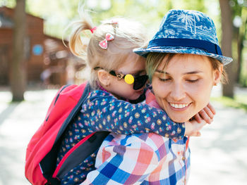 Close-up smiling mother giving piggyback ride to daughter