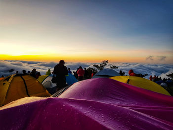 People by tents against sky during sunset