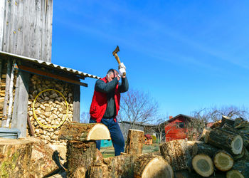 Spring landscape with a man in a red vest, a man in his yard splits firewood, climate change