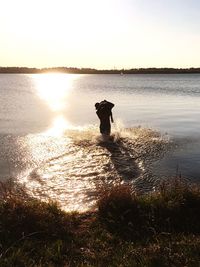 Silhouette man standing by sea against clear sky during sunset