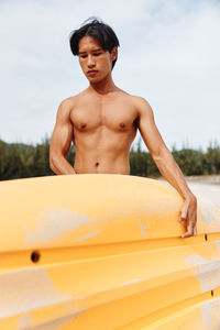 Portrait of shirtless man standing against sky