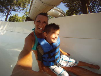 Portrait of smiling young woman and boy on slide