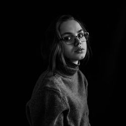Portrait of beautiful woman in eyeglasses against black background