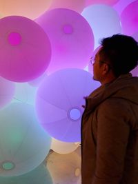 Side view of boy with pink balloons