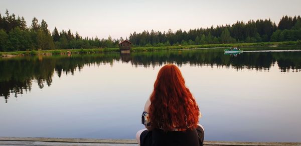 Rear view of woman looking at lake against sky