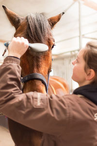 Woman cleaning horses at stable