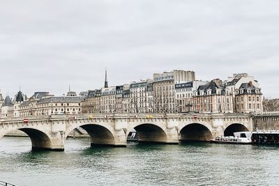 Arch bridge over river against sky in city