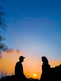 Silhouette people standing against dramatic sky during sunset