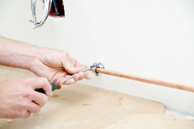 Cropped hands of man adjusting pipe on wall