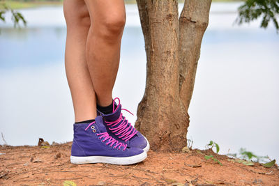 Low section of woman standing by lake