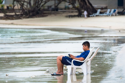 Side view of man sitting at beach