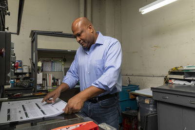 Male employee examining copies on machine in print shop