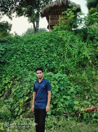 Portrait of young man standing against plants