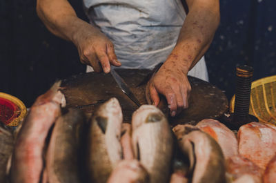 Midsection of woman cleaning fish at market for sale