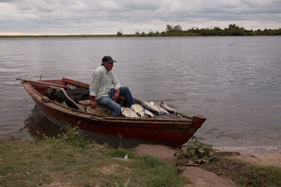 Man sitting in fishing boat on lake