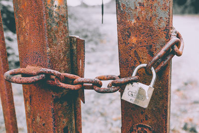 Close-up of rusty metal chain against fence