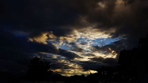 Low angle view of silhouette trees against cloudy sky
