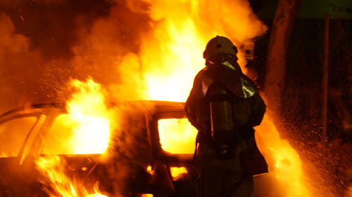 Man standing by fire burning at night