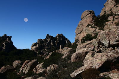 Low angle view of rocks against clear blue sky