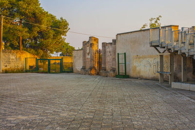 Empty road by buildings against sky