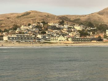 Scenic view of town by sea against sky