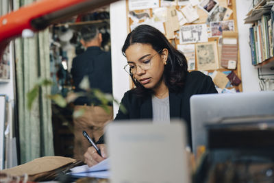 Female store owner wearing eyeglasses and working at antique store